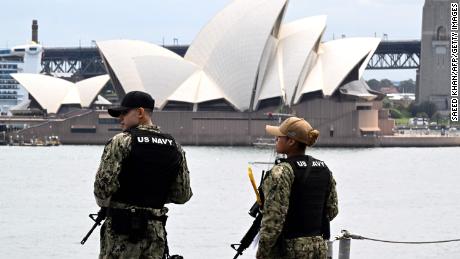 Australia&#39;s landmark Opera House is seen past military personnel on board the US Navys USS Tripoli (LHA-7) amphibious assault ship while docked at fleet base in Sydney on November 4, 2022. - The USS Tripoli and her 1,200-strong crew made a port call as part of routine operations in the Indo-Pacific.