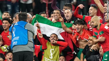 Morocco&#39;s team makes a group photo on the pitch, holding the Palestinian flag after beating Spain.
