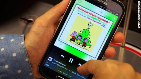 A woman listens to music from &quot;A Charlie Brown Christmas&quot; on her phone in 2013. 