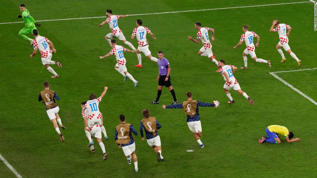 Croatian players run around the field and celebrate their victory as Marquinhos, bottom right, falls to his knees.