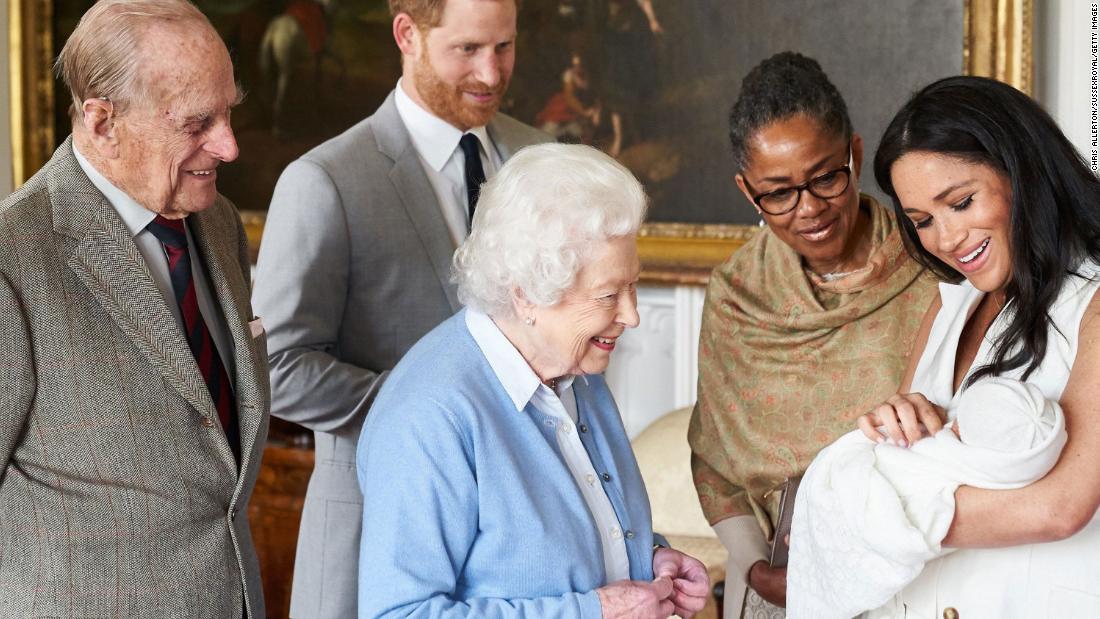 Queen Elizabeth II looks at her new great-grandchild, Archie, in May 2019. Prince Philip is on the far left. Meghan&#39;s mother, Doria Ragland, is next to her at right.
