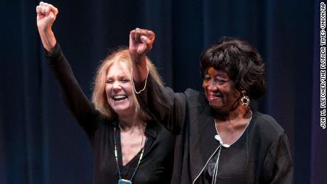 Gloria Steinem, left, and Dorothy Pitman Hughes raise their fists together, looking like a photograph taken at the height of their activism together, at the Lazarra Theater at the University of North Florida in Jacksonville, Florida, during a conference March 10.  2011. Hughes, a pioneering black feminist, child protection advocate and activist who formed a powerful speaking partnership with Steinem and appeared with her in one of the feminist movement's most iconic photos, died.  Hughes died on December 1, 2022 in Tampa, Florida.  She was 84 years old. 