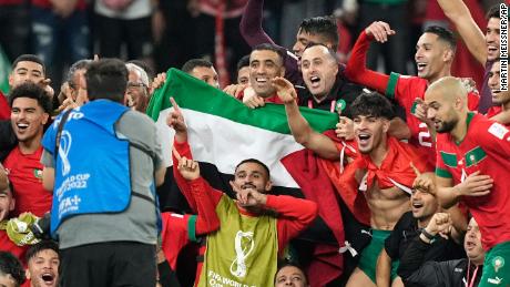 Morocco&#39;s team poses with the Palestinian flag after beating Spain on December 6. 