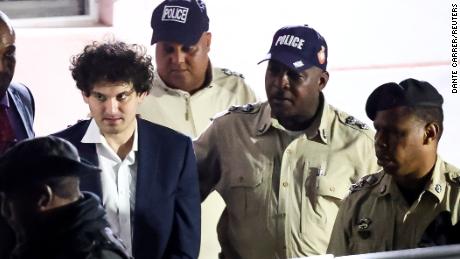 Sam Bankman-Fried, who founded and led FTX until a liquidity crunch forced the cryptocurrency exchange to declare bankruptcy, is escorted out of the Magistrate Court building in Nassau, Bahamas December 13, 2022. REUTERS/Dante Carrer