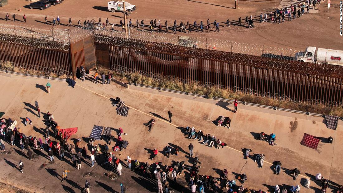 After crossing the Rio Grande, migrants line up near the border wall to turn themselves in to US Border Patrol agents on December 13.