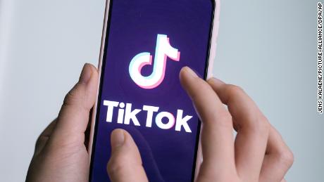 A girl is holding her smartphone with the logo of the short video app TikTok in her hands. 