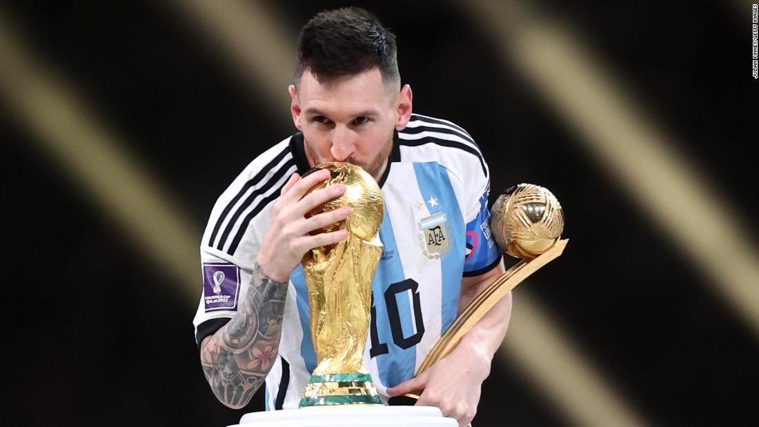 Messi holds the Golden Ball trophy, awarded to the tournament&#39;s top player, while kissing the World Cup trophy.