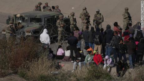 A group of migrants are waiting on the US side of the Rio Grande as the Texas National Guard blocked access to parts of the border with barbed wire and vehicles as seen from Ciudad Juarez, Mexico, on December 20, 2022.