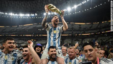 LUSAIL CITY, QATAR - DECEMBER 18: Lionel Messi of Argentina celebrates with the FIFA World Cup Qatar 2022 Winner&#39;s Trophy on Sergio &#39;Kun&#39; Aguero&#39;s shoulders after the team&#39;s victory during the FIFA World Cup Qatar 2022 Final match between Argentina and France at Lusail Stadium on December 18, 2022 in Lusail City, Qatar.  (Photo by David Ramos - FIFA/FIFA via Getty Images)