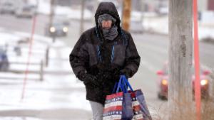 Greg Behrens, of Des Moines, Iowa, tries to stay warm as he makes his way on a snow covered sidewalk, Wednesday, Dec. 21, 2022, in Des Moines, Iowa. (AP Photo/Charlie Neibergall)