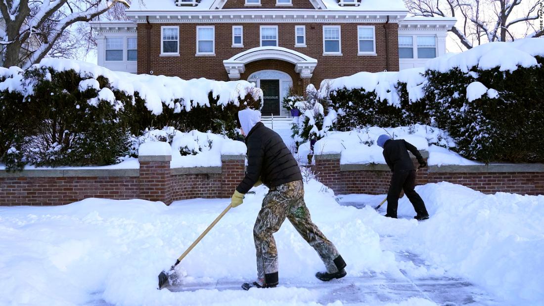 Kids shovel snow off a sidewalk and driveway in Minneapolis on December 22.