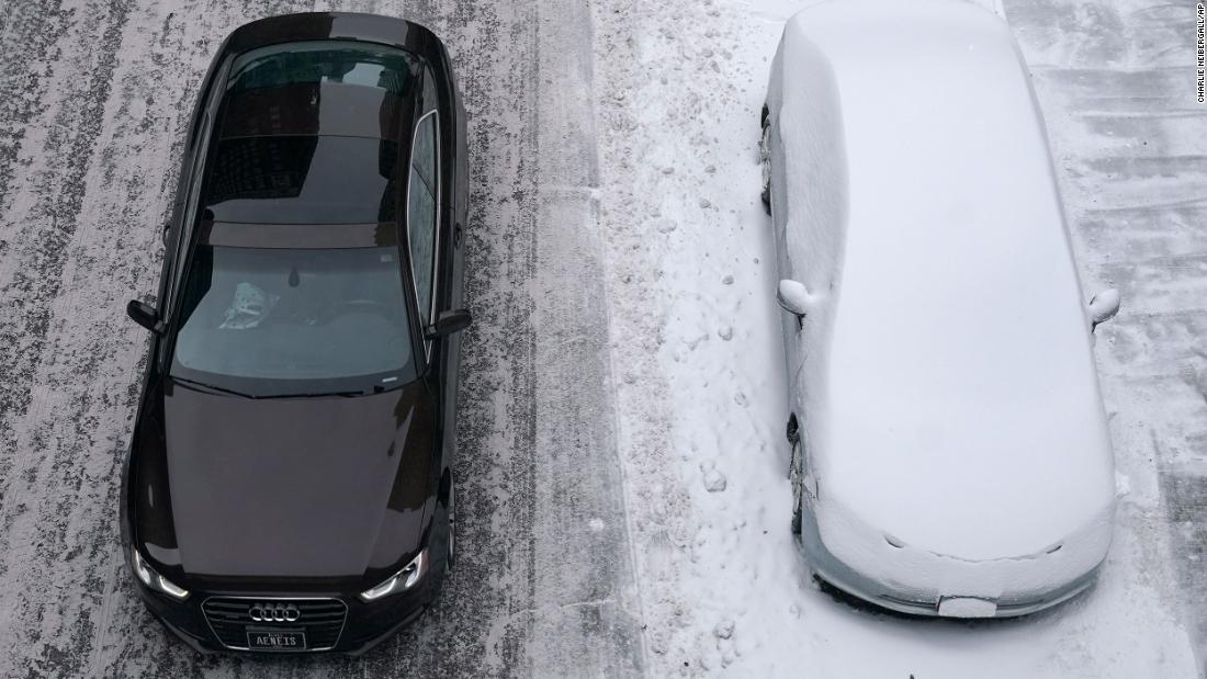 A clean car passes a snow-covered car in Des Moines, Iowa.
