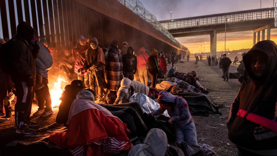 Migrants warm themselves by a fire next to the US-Mexico border fence in El Paso, Texas, on Thursday, December 22.