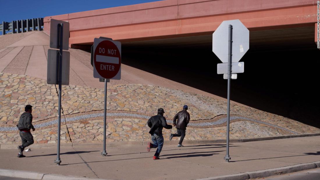 Migrants run into the street after crossing into the United States through a hole in an El Paso fence on December 22.