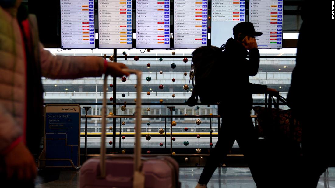 Travelers walk in front of flight information screens at O&#39;Hare International Airport in Chicago on December 22.