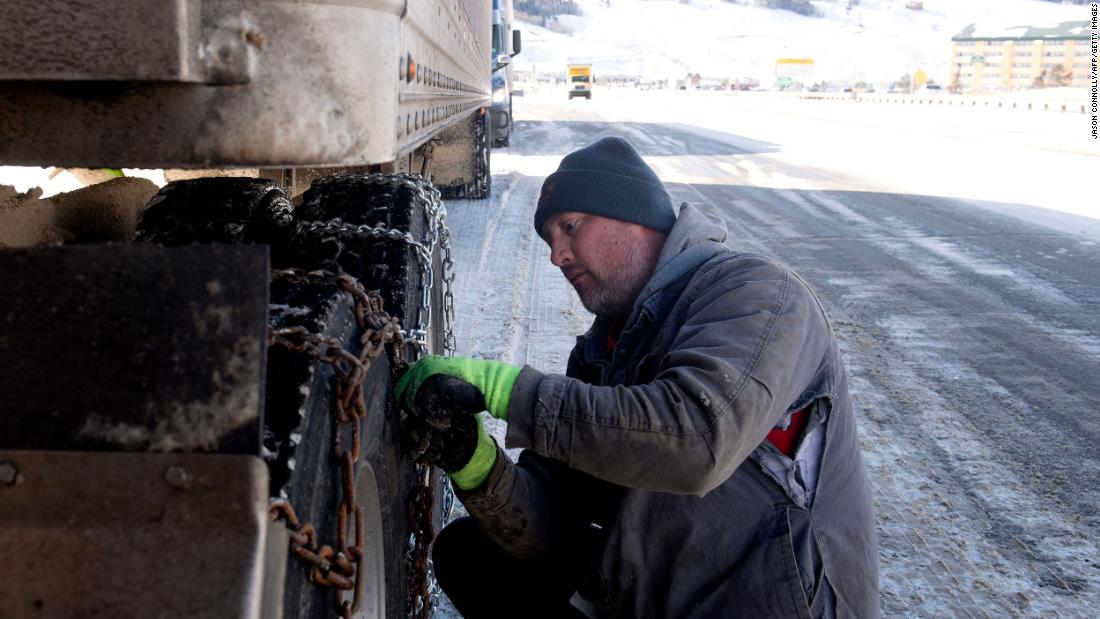 Robert Arnold puts chains onto the tires of his semitrailer while he waits for the eastbound lane of I-70 to reopen in Silverthorne, Colorado, on December 22.