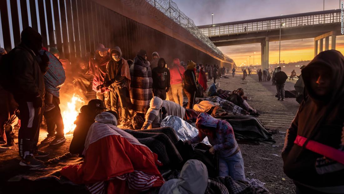 Migrants warm themselves by a fire next to the US-Mexico border fence on December 22 in El Paso, Texas.