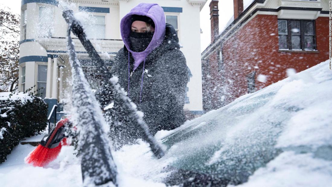 Amanda Kelly cleans off snow and ice from her car in Columbus, Ohio, on Friday, December 23.
