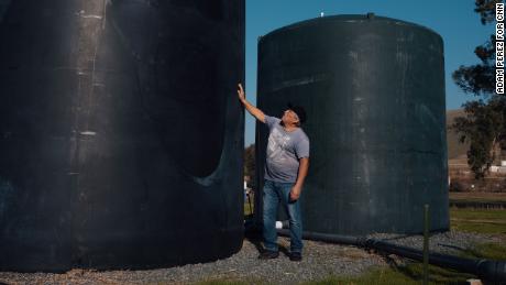 Benjamin Cuevas stands next to a town water tank in Tooleville.