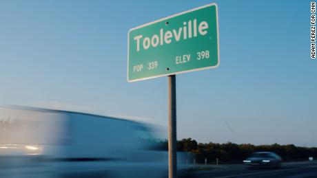 Cars drive past a sign on the outskirts of Tooleville.