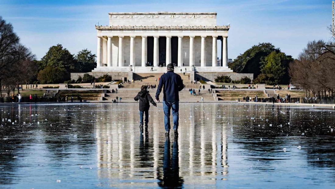 A man and a boy walk across the frozen Reflecting Pool towards the Lincoln Memorial in Washington, DC, on December 26.
