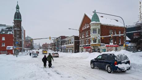 People and vehicles move about Main St. in Buffalo, N.Y., Monday, December 26, 2022, after a massive snow storm blanketed the city. 