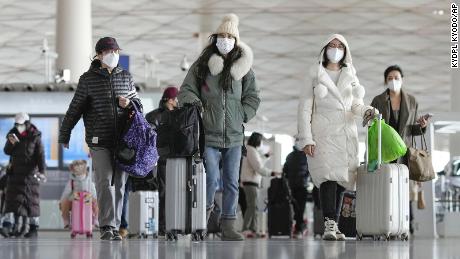 Passengers wearing face masks pull baggage at a departure lobby in Beijing Capital International Airport on Dec. 27, 2022, after the central government recently dropped its &quot;zero-Covid&quot; policy. 