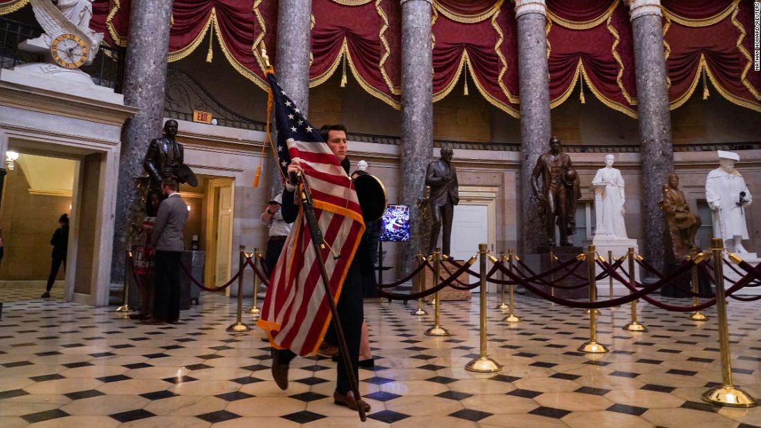 A congressional staff member carries an American flag though the Capitol&#39;s Statuary Hall on Tuesday.