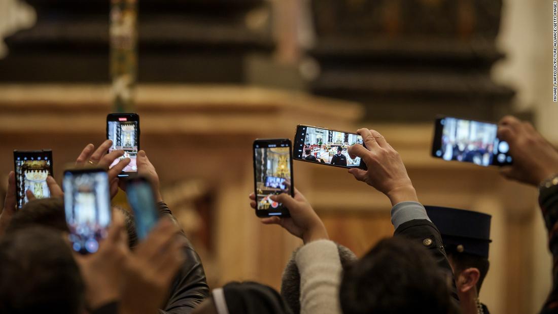People take pictures of the late Pope on Monday.