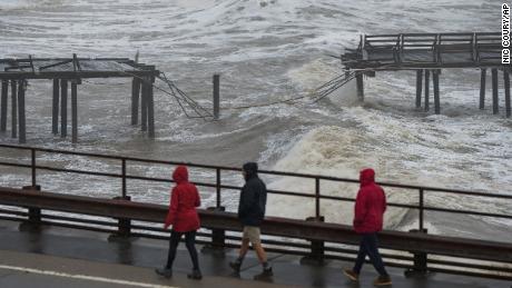 People walk along Cliff Drive to view the Capitola Wharf damaged by heavy storm waves in Capitola on January 5, 2023. 