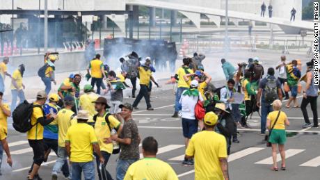 Supporters of Brazilian former President Jair Bolsonaro clash with the police during a demonstration outside the Planalto Palace in Brasilia on January 8, 2023. - Brazilian police used tear gas Sunday to repel hundreds of supporters of far-right ex-president Jair Bolsonaro after they stormed onto Congress grounds one week after President Luis Inacio Lula da Silva&#39;s inauguration, an AFP photographer witnessed. (Photo by EVARISTO SA / AFP) (Photo by EVARISTO SA/AFP via Getty Images)