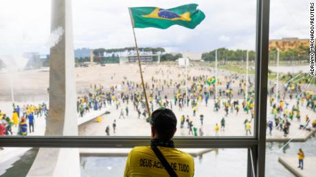 A man waves Brazil&#39;s flag as supporters of former President Jair Bolsonaro demonstrate outside the National Congress in Brasília, Brazil, on Dec. 8, 2023.