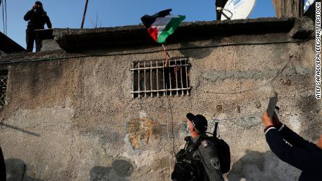 A woman waves a Palestinian flag from her window during clashes with Israeli police following on February 18, 2022.