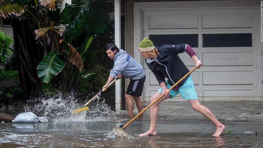 Evan Sousa, left, gets help from Calvin Drake as they push water out of his flooded apartment in Pacifica on January 5.