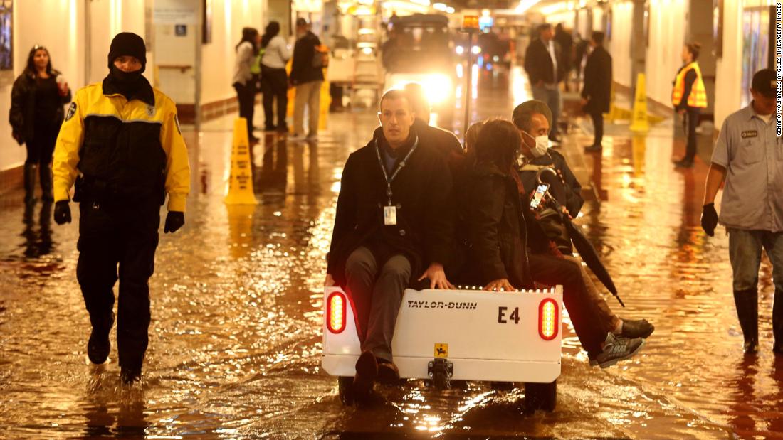 Commuters in downtown Los Angeles are shuttled over a flooded section of a pedestrian walkway leading to train platforms on the main level of Union Station.