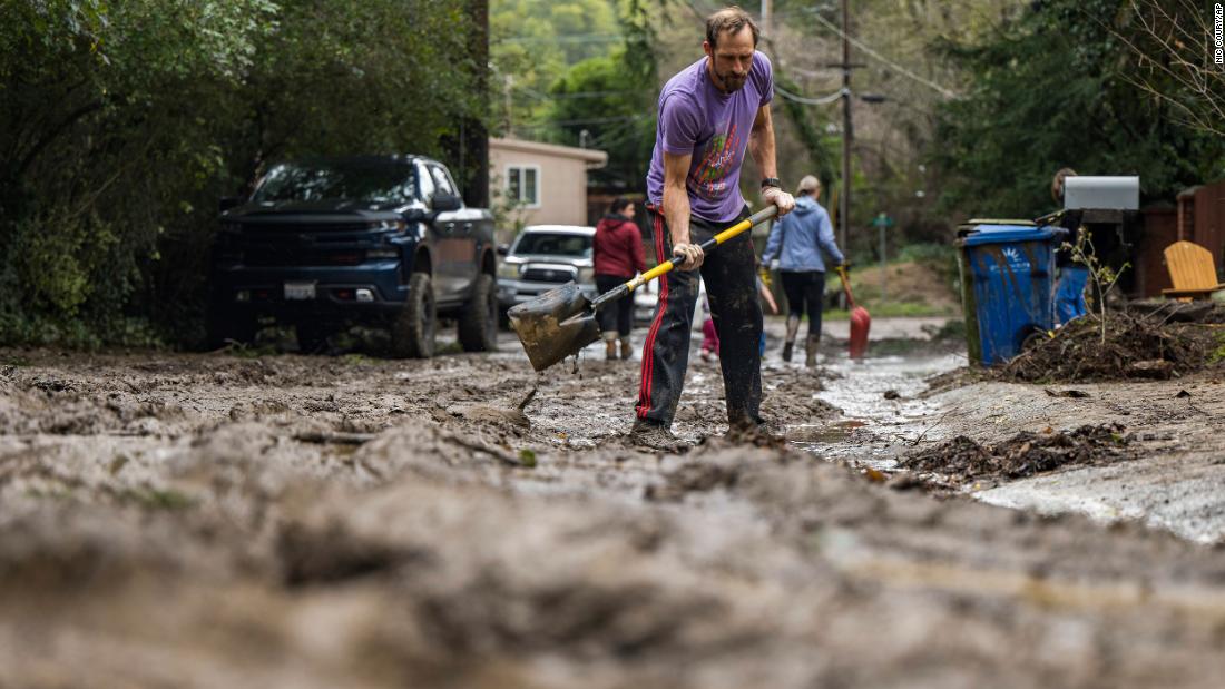 Matt O&#39;Brien shovels mud from a driveway on January 10 after the San Lorenzo River overflowed in Felton.