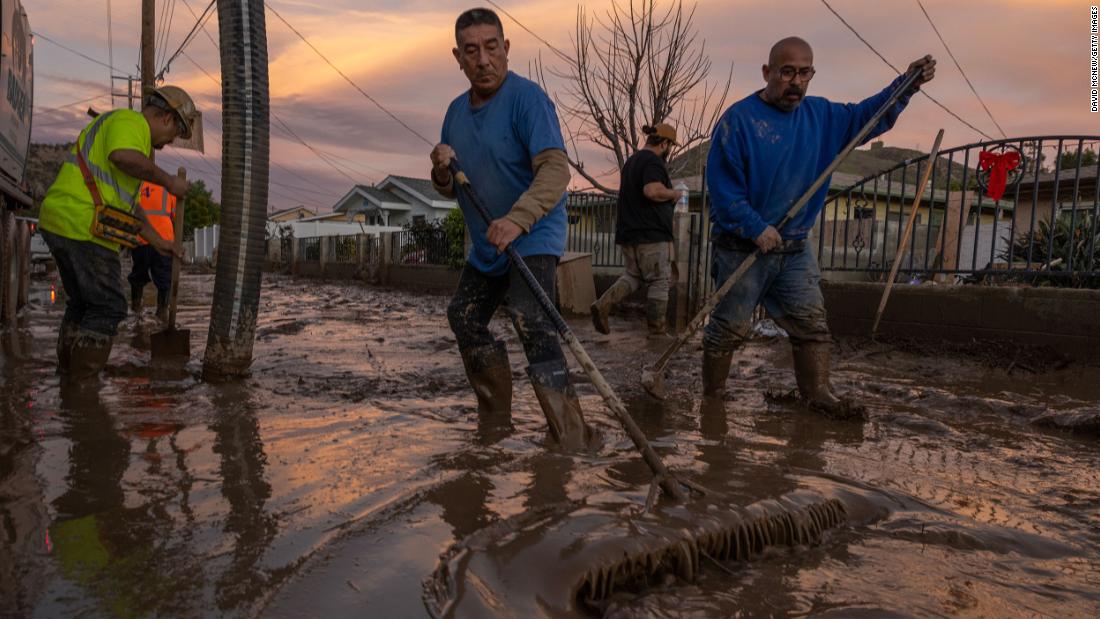 Residents in Piru work to push back wet mud that trapped cars and invaded some houses on January 11.