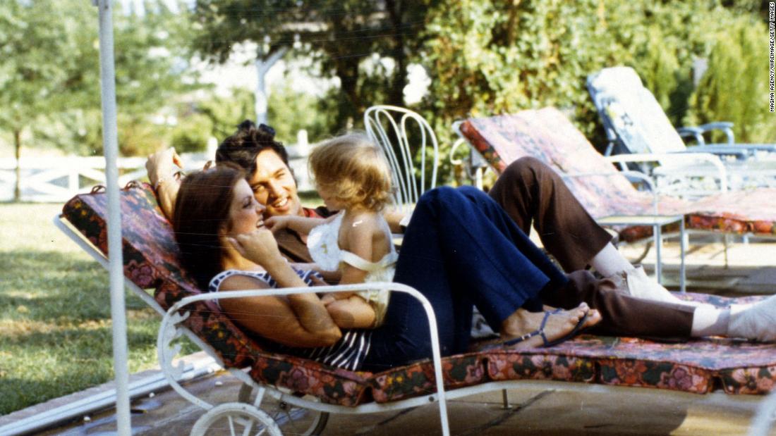 Lisa Marie Presley sits on her mother&#39;s lap while enjoying a day with her parents.