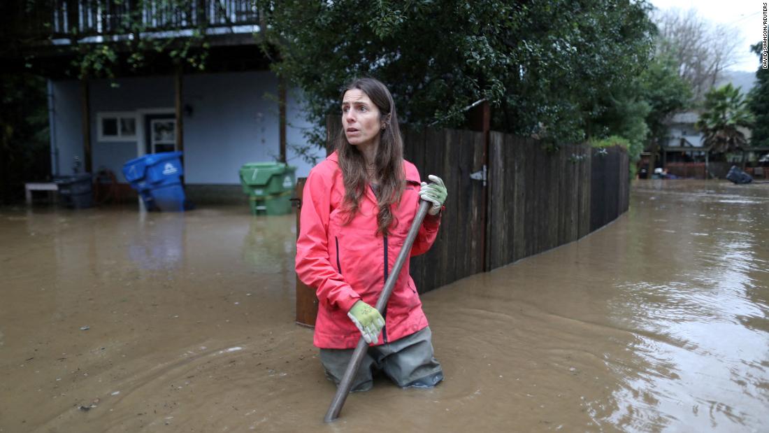 Melissa Foley clears debris in her neighborhood as the San Lorenzo River rises in Felton on Saturday, January 14.