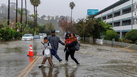 People walk on a flooded street in San Diego Monday.