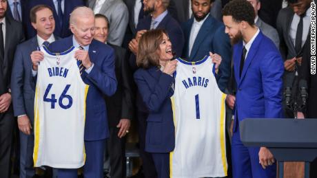 President Joe Biden holds up a jersey with &quot;Biden&quot; and &quot;46&quot; printed on the back and Vice President Kamala Harris holds up a jersey with &quot;Harris&quot; and &quot;1&quot; printed on the back as Stephen Curry looks on during an event to honor the 2022 NBA champion Golden State Warriors in the East Room of the White House on January 17, 2023, in Washington, DC. 