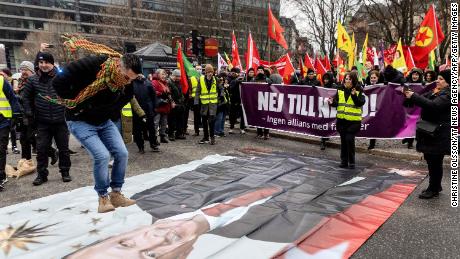 A participant jumps on a banner showing a portrait of Turkish President Recep Tayyip Erdogan during a demonstration in Stockholm on January 21, 2023. 