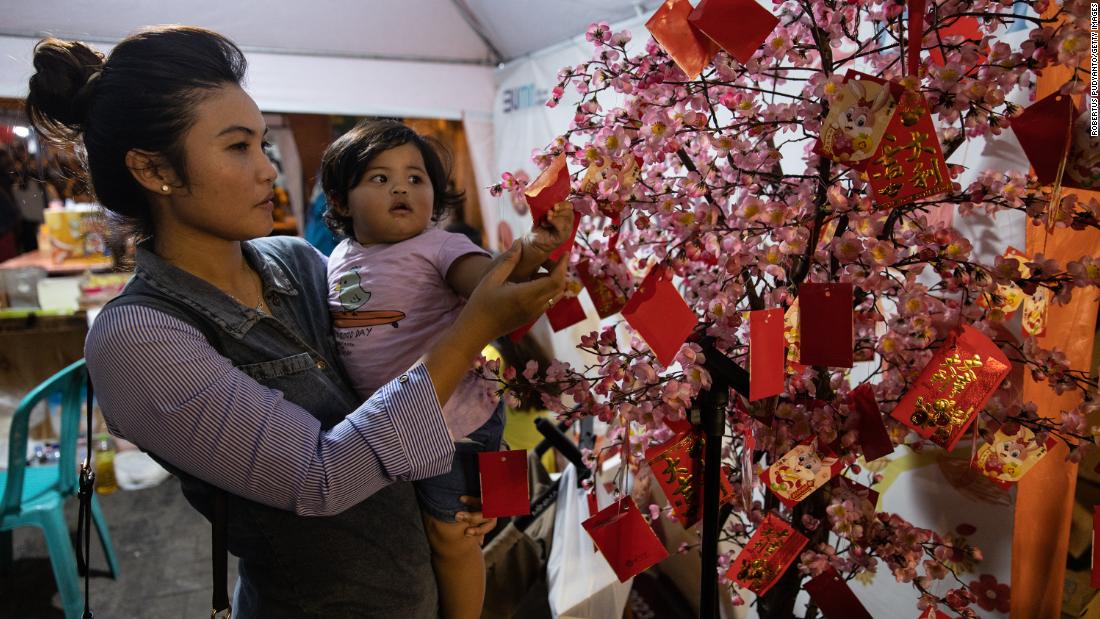 A girl reaches Chinese fortune tree during Lunar New Year celebrations on January 22, in Semarang, Java, Indonesia.