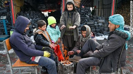 Afghans gather around a bonfire after snowfall in Kabul on January 23, 2023. 