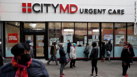 People wearing protective face masks wait in line outside a CityMD Urgent Care in the Bronx borough of New York during the COVID-19 outbreak in November 2020. 