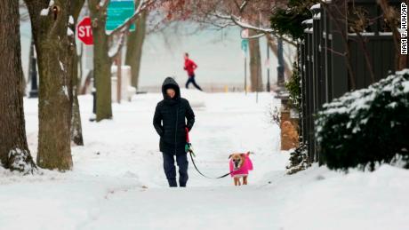A woman takes a walk with her dog on a snow-covered sidewalk Sunday in Evanston, Illinois. 
