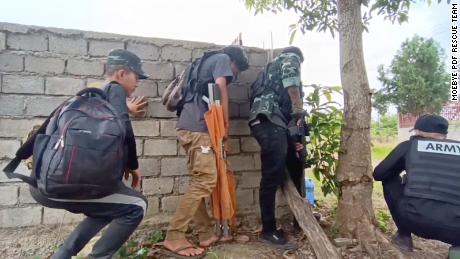 Combat medics from the Moebye PDF Rescue Team hide behind a wall as they prepare to rescue rebel fighters in Moe Bye, Myanmar, on September 9, 2022.
