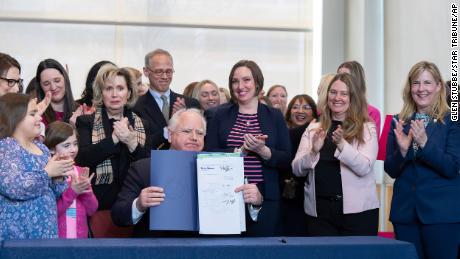 Surrounded by DFL legislators, Minnesota Gov. Tim Walz, center, holds up a bill he signed that adds a &quot;fundamental right&quot; to abortion access into state law on Jan. 31, 2023, in St. Paul, Minn. 