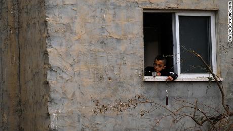 A child plays by a window, next to the building that was destroyed.