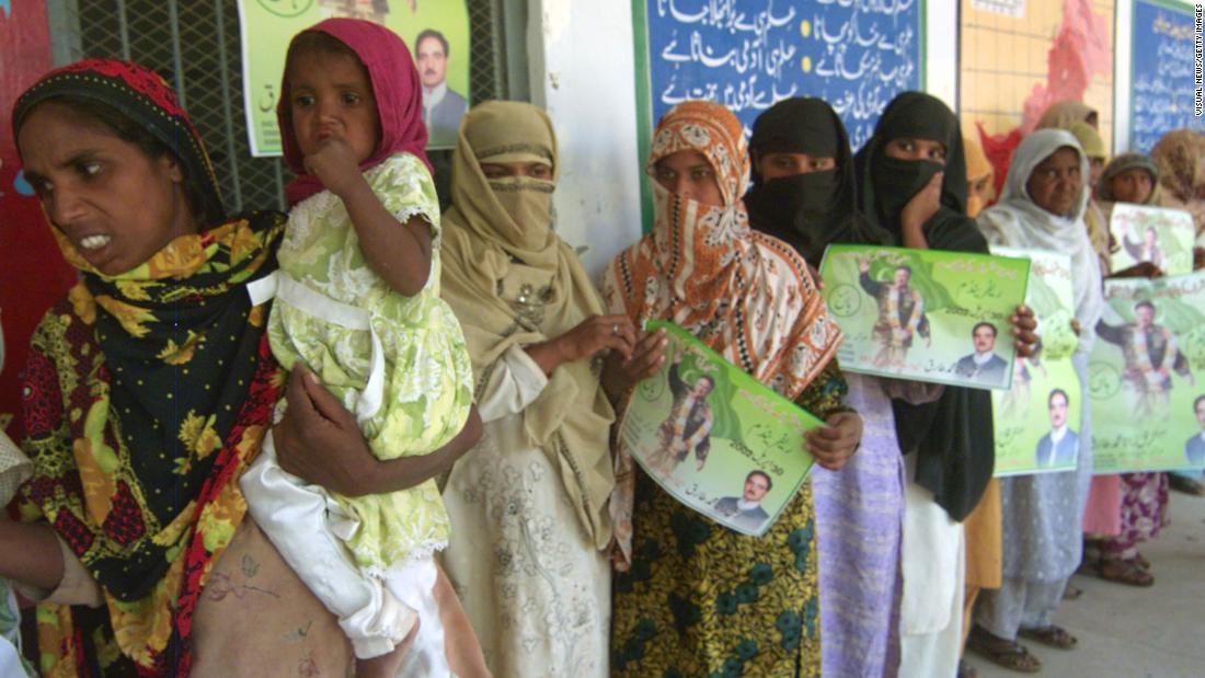 Pakistani women hold pictures of Musharraf as they stand outside a polling station in Lahore during the 2002 referendum.